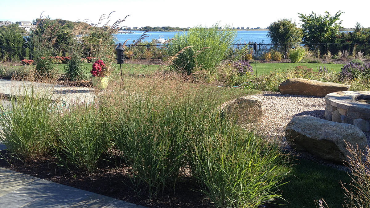 Ornamental Grasses and fire pit in front of water in Charleston, Rhode Island