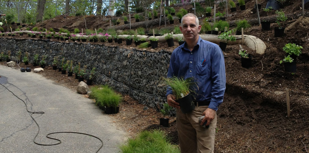 Tom Benjamin, Landscape Architect, Standing In Front Of Rock Wall